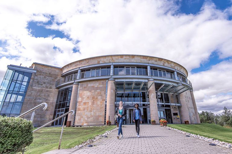 Two students walk on the path out of the Gateway Building